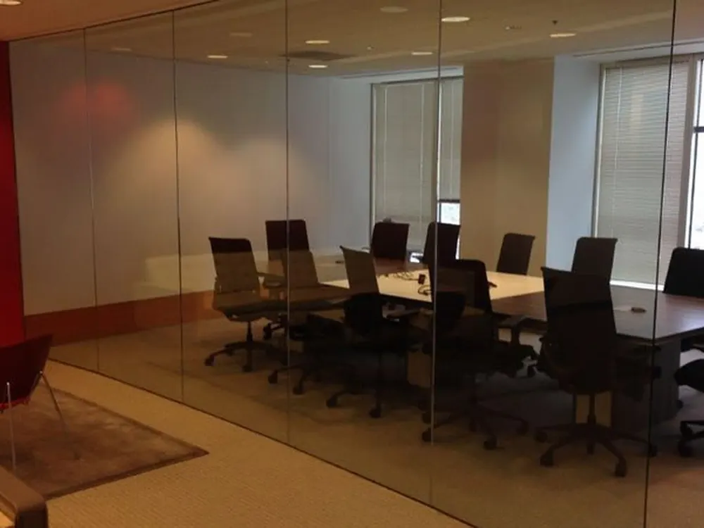 A glass-walled conference room with nothing on the glass, fully exposed to the floor outside.